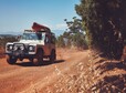 Portrait of  car driving on country road with canoe on top. Countryside road trip.