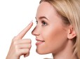 Young woman holding contact lens on index finger with copy space. Close up face of healthy beautiful woman about to wear contact lens. Eyesight and ophthalmology concept.