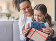 Mother and little daughter girl unwrapping unpacking birthday Christmas Mothers day present gift box on family celebration event at home