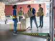 4 men Warehouse worker open doors steel 40 feet container and help carry box one by one supervisor stand near by using paper clip checklist