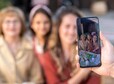 Hands of man taking photo of little girl, her mother and grandmotehr, focus on screen,